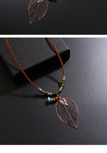 Détail du pendentif feuille bohème avec filigrane en bronze et perles colorées