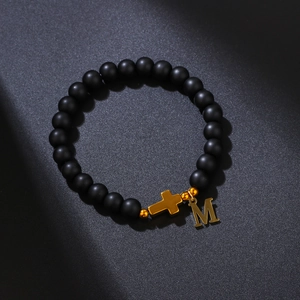 8mm matte black beaded bracelet featuring a gold cross charm and letter M pendant