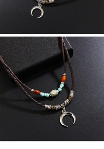 Detail of vintage bohemian crescent moon pendant with turquoise beads and leather cord