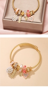 Detail of a handmade golden spiral charm bracelet with pink crystals and pearls