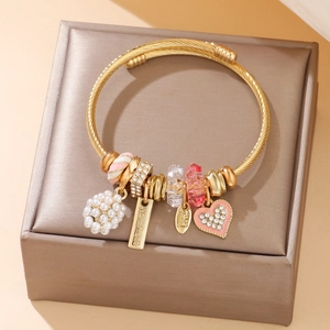 Golden handmade charm bangle with pearls and heart pendant on a soft satin box