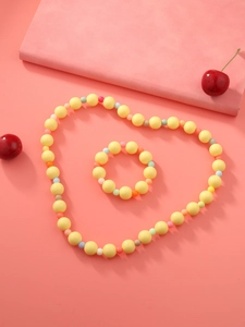 Vue à plat d'un ensemble collier et bracelet en perles acryliques jaunes en cœur