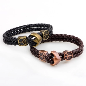 Detail view of woven leather bracelets with vintage anchor hooks and peace sign charms