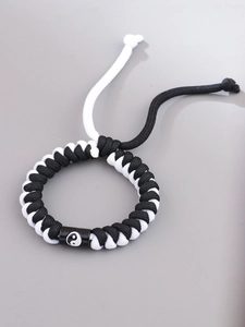 Close-up of black and white braided rope bracelet with a Yin Yang symbol bead and adjustable drawstring