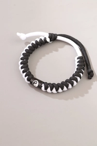 Detail of woven black and white rope bracelet featuring a Tai Chi Yin Yang symbol charm