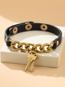 Detail van een punk zwart lederen beenring met gouden kettingen en sleutelhangers