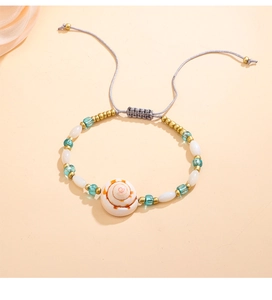 Dettaglio del bracciale bohémien con conchiglia naturale e perline blu per un look estivo