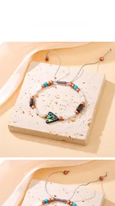 Détail du pendentif en nacre d'abalone et des perles sur le bracelet tressé ajustable