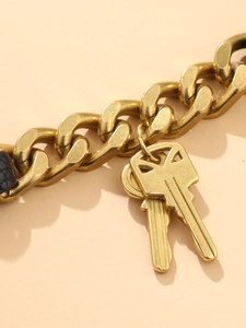 Detail van een gouden punkketting met sleutelhangers en een vintage metalen textuur