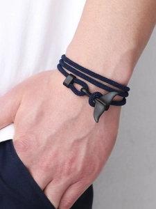 Close-up of men's navy braided bracelet with matte black whale tail metal clasp detail