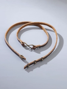 Detailed view of vintage brown leather bracelet with bronze infinity buckle and adjustable snaps