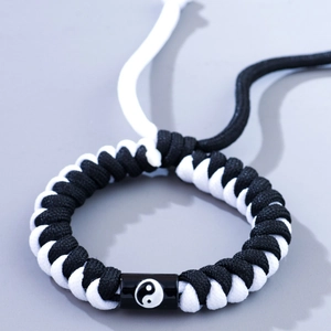 Braided couple's bracelet featuring yin yang tai chi charm in black and white cords