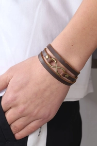 Detail of multi-layer leather bracelet with bronze infinity symbol and metallic rivets