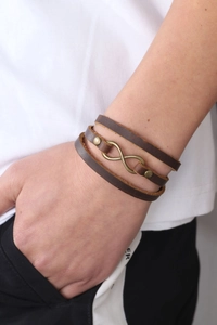 Detail of multi-strand brown leather bracelet with bronze infinity symbol and rivets