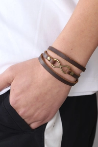 Close-up of vintage brown leather multi-layer wrap bracelet with bronze infinity symbol