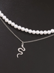 Close-up of double-layer necklace featuring white pearls and a silver snake pendant detail