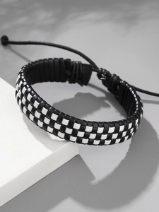 Détail du bracelet en cuir tressé à damier avec cordon de serrage noir réglable et nœud