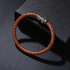Brown braided leather bracelet with vintage silver metal fleur-de-lis charm on black stand