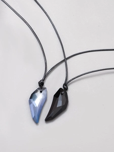 Detail of wolf tooth crystal couple pendants with faceted gray-blue and black finishes