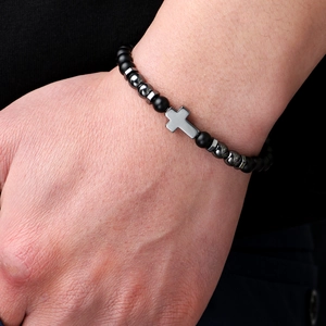 Men's matte black beaded bracelet with silver cross pendant on a textured dark sleeve