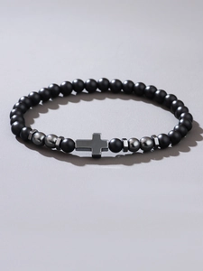 Detail of matte black beads bracelet with metallic cross and polished accents