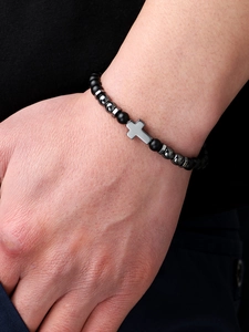 Close-up of men's black matte beaded bracelet with silver cross and metallic accents