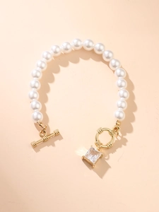 Detail of elegant pearl bracelet featuring a gold OT toggle clasp and square zircon pendant