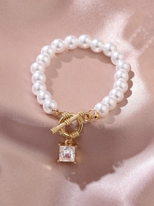 Macro shot of pearl bracelet with golden OT toggle clasp and square zircon pendant