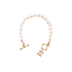 Elegant pearl bracelet with golden toggle clasp and square crystal pendant on white background