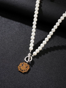 Detail der Perlenkette mit verpixeltem gelbem Smiley-Anhänger und silbernem OT-Verschluss