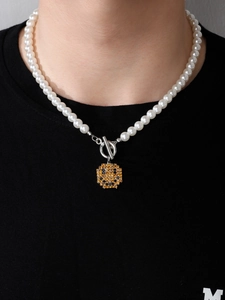 Detail einer Perlenkette mit OT-Verschluss und quadratischem Smiley-Anhänger im Pixel-Stil