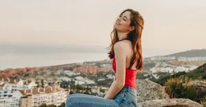 Chic red backless knit top paired with light blue denim jeans on a scenic mountain top
