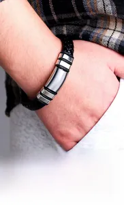 Close-up of men's braided leather bracelet with polished steel tube worn with casual style