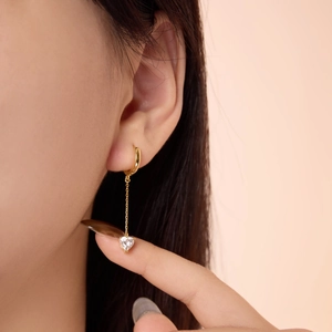 Detail of S925 silver heart dangle earring with gold plating on a model ear