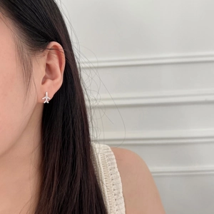 Close-up of S925 sterling silver airplane stud earring with sparkling cubic zirconia on model