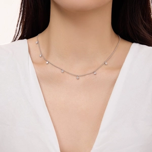 Detail of S925 sterling silver beaded necklace with small round zircon pendants on a model