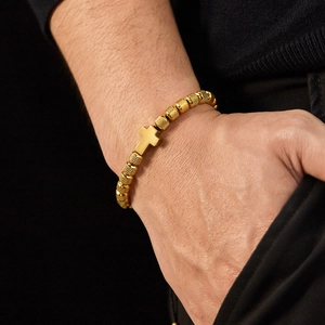 Bracelet pour homme avec perles dorées texturées et pendentif croix sur le poignet