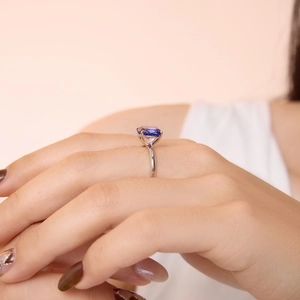 S925 sterling silver ring with cushion cut blue gemstone on finger in soft lighting