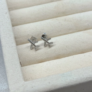 Macro shot of silver airplane stud earrings with zirconia accents on fabric display