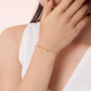Détail d'un bracelet fin en argent S925 doré avec gemmes roses et pendentif cœur élégant