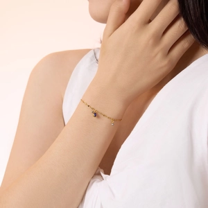 Detail of a delicate gold chain bracelet with three blue teardrop gemstone pendants