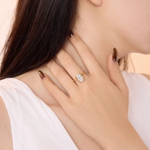 Macro shot of an oval-cut emerald stone ring on hand with elegant gold bezel setting