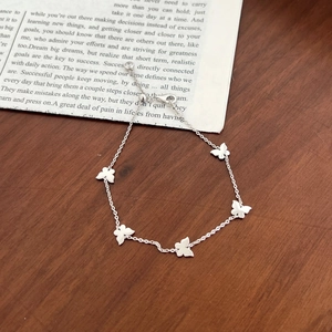 Minimalist S925 sterling silver butterfly bracelet with five matte charms on a wooden table