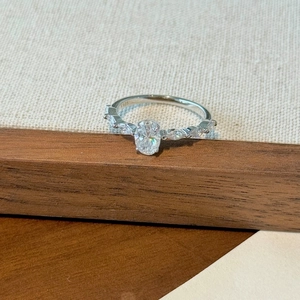 Elegant S925 sterling silver ring with oval cut moissanite on a walnut wood stand