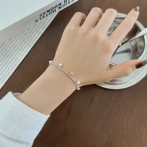 Bracelet en argent sterling S925 avec perles et breloques cœur sur une table en bois brun