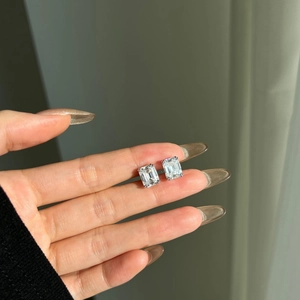 Dettaglio ravvicinato di orecchini in moissanite taglio smeraldo in argento 925 sulla mano