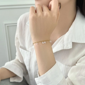 Delicate gold link bracelet with sparkling teardrop charms on a model's wrist