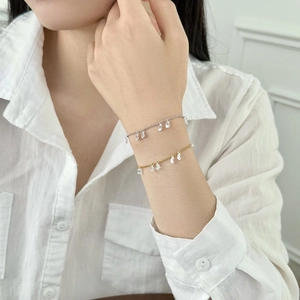 Close-up of layered S925 silver bracelets with teardrop crystal pendants on a model's wrist