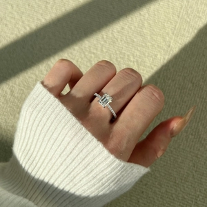 Detail of 2 carat emerald cut moissanite ring with pavé diamond band on hand