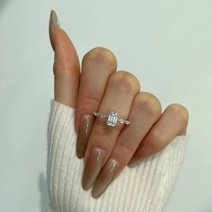 Macro detail of emerald cut moissanite silver ring worn over a white knit sweater sleeve